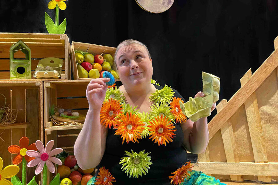 Aurore, la comédienne, dans son décor, tout en bois avec ses fleurs, ses pommes et ses œufs, entouré de ses amis, les poules et les coqs au clair de lune.