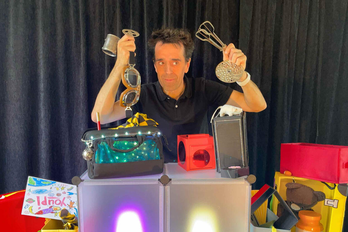 Zouick, fouick, Touick Photo de Monsieur Fred en pleine représentation, entouré de souvenirs et de surprises pour les enfants lors du spectacle “Zouick, fouick, touick”.
