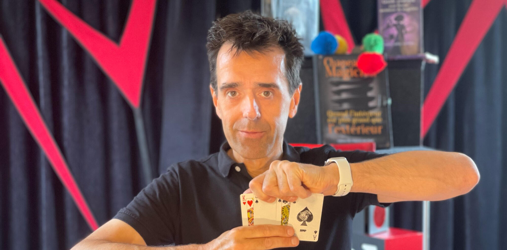 C'est magique ! Monsieur Fred fait apparaître un lapin en peluche à partir d’un foulard, entouré de ballons rouges, lors d’un numéro de magie pour enfants